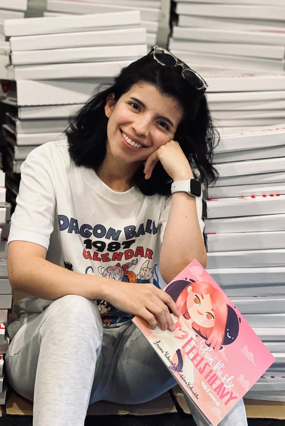 Luciana sitting beside copies of the book